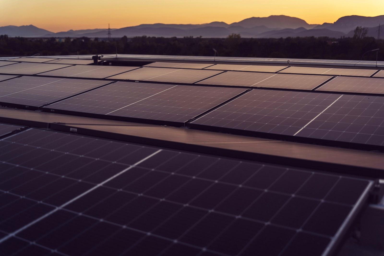 Cubierta de nave industrial con hileras de paneles solares al atardecer