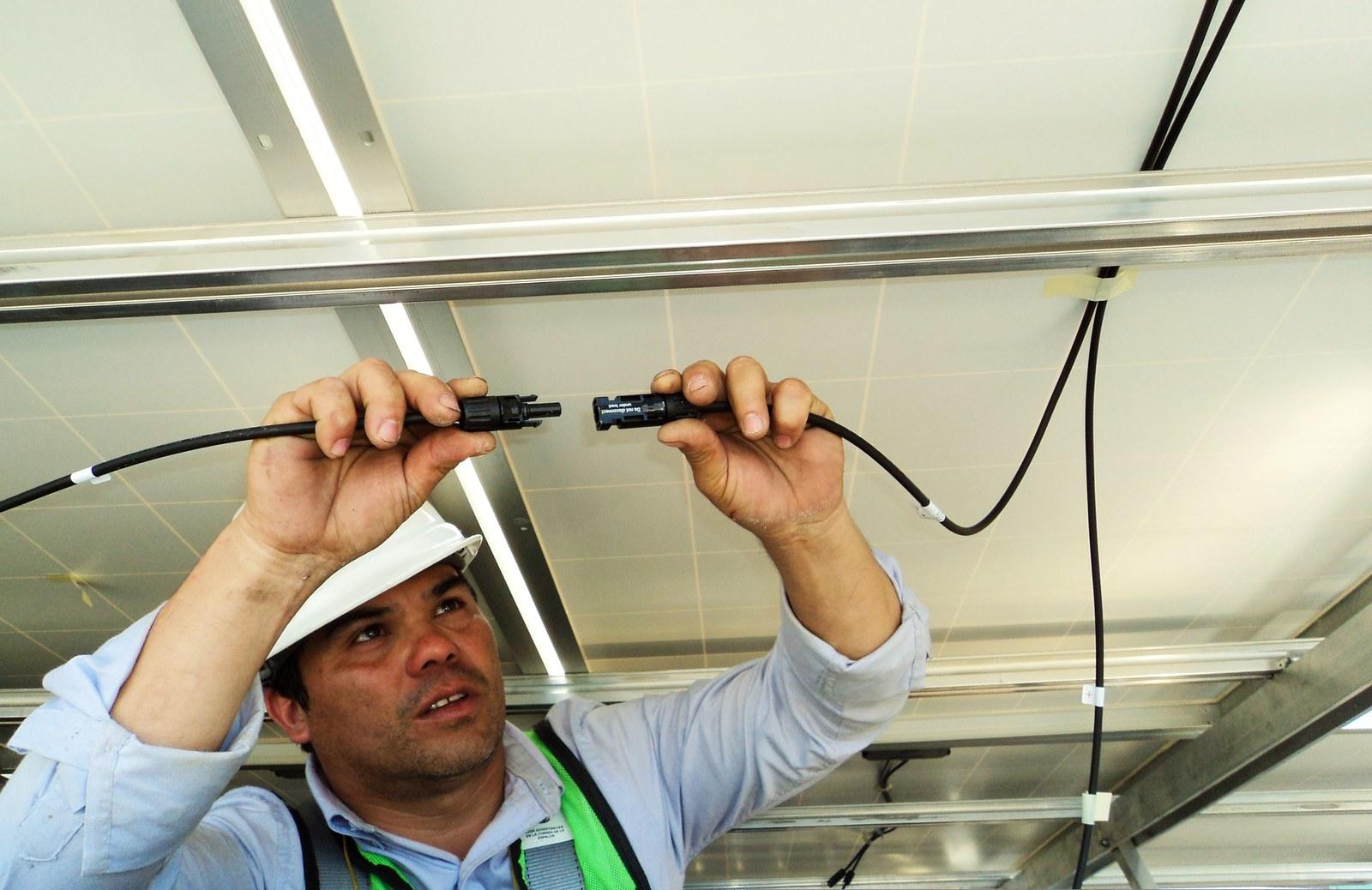 Técnico realizando la conexión eléctrica bajo los paneles